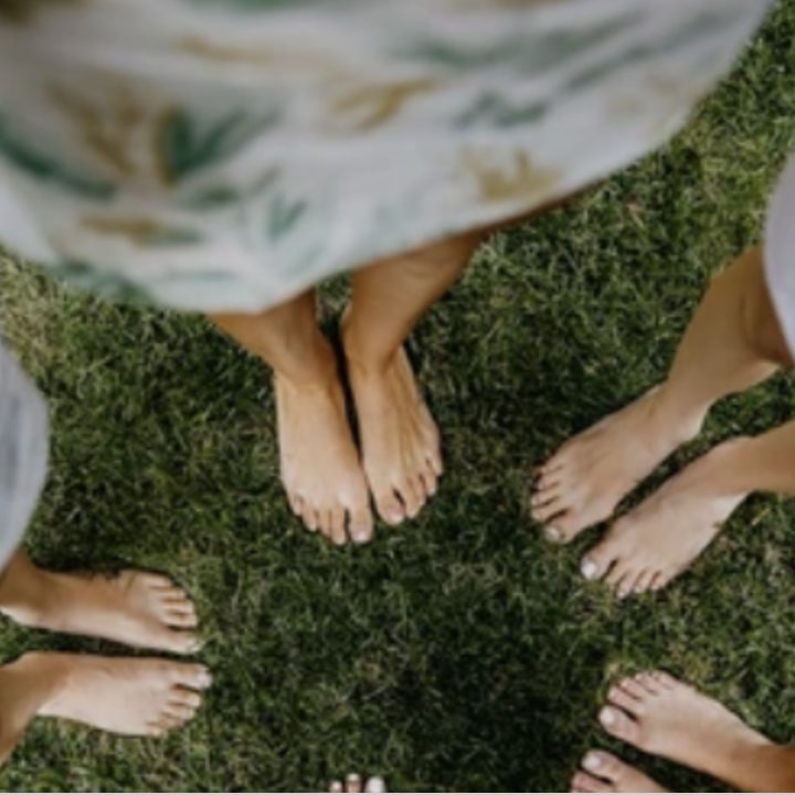 Bare feet gathered in a circle on the grass